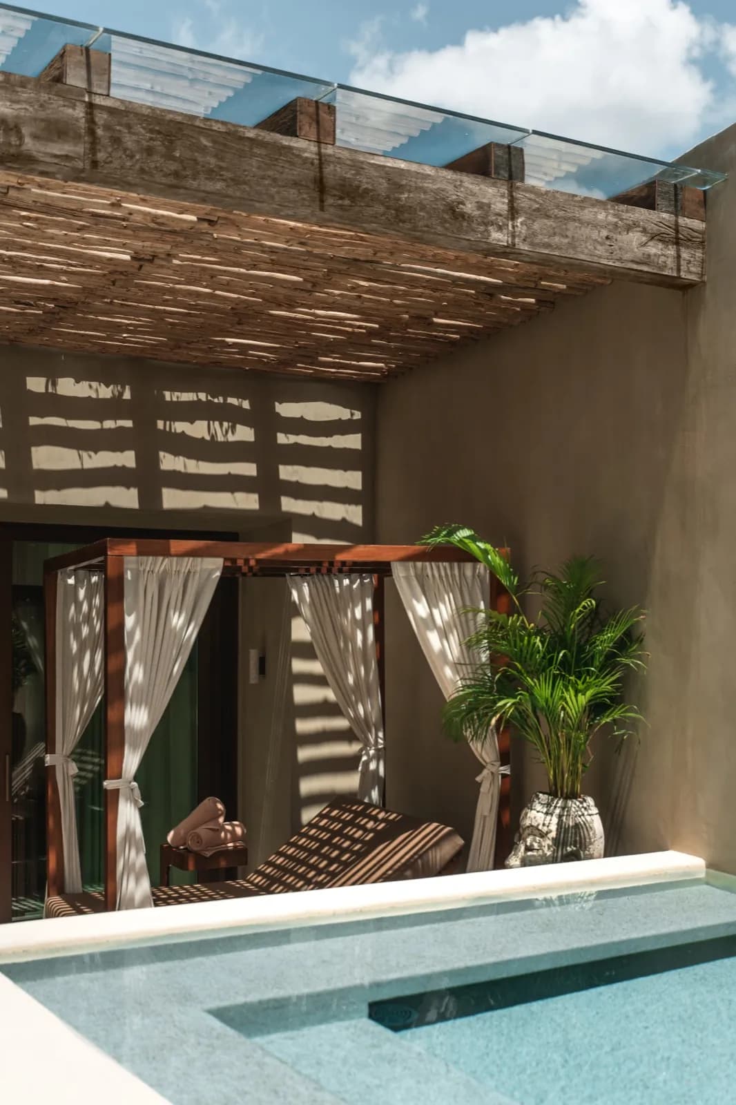 Vertical view of a courtyard plunge pool with canopy daybed and palm
