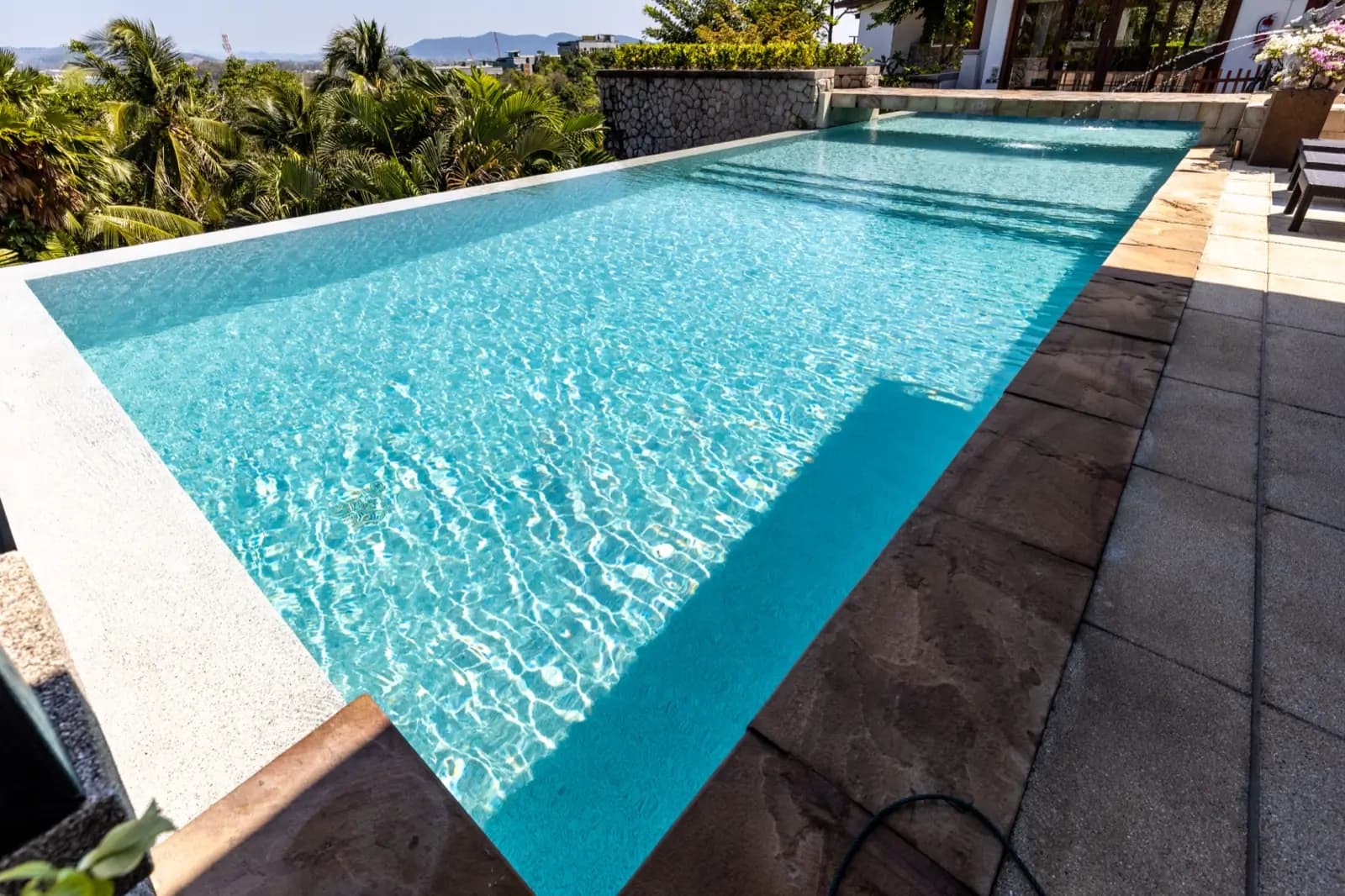 Rippling light-aqua pool running along a sandstone deck