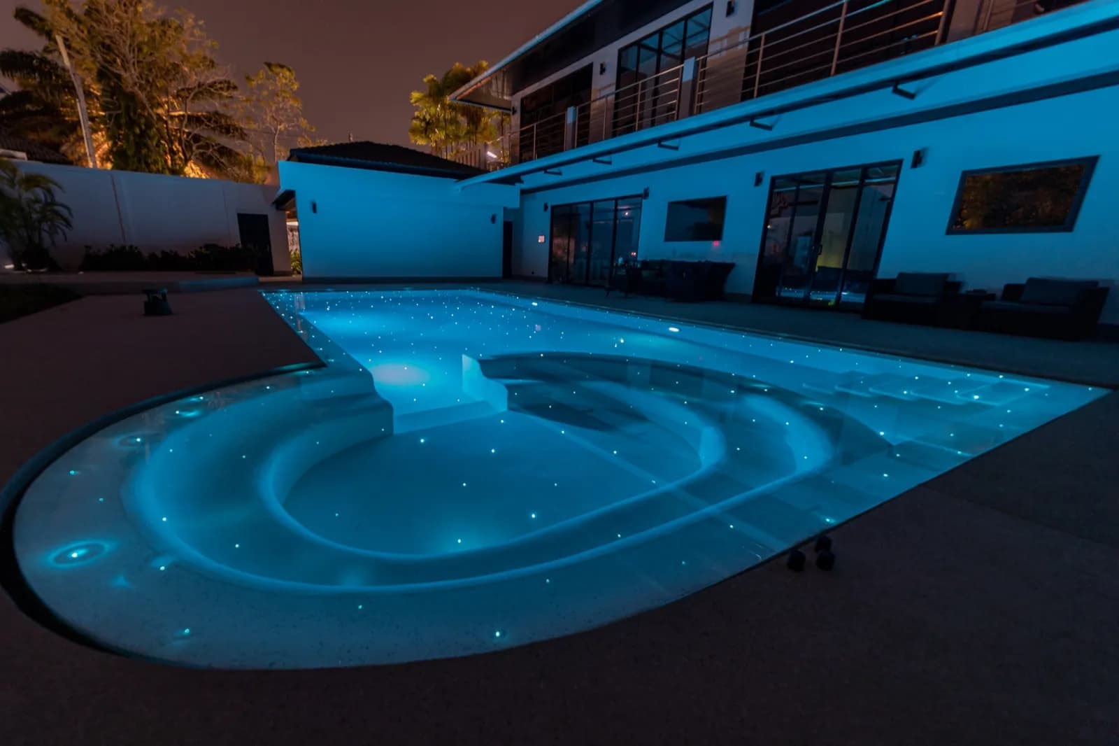 Villa and keyhole pool bathed in cyan light after dark