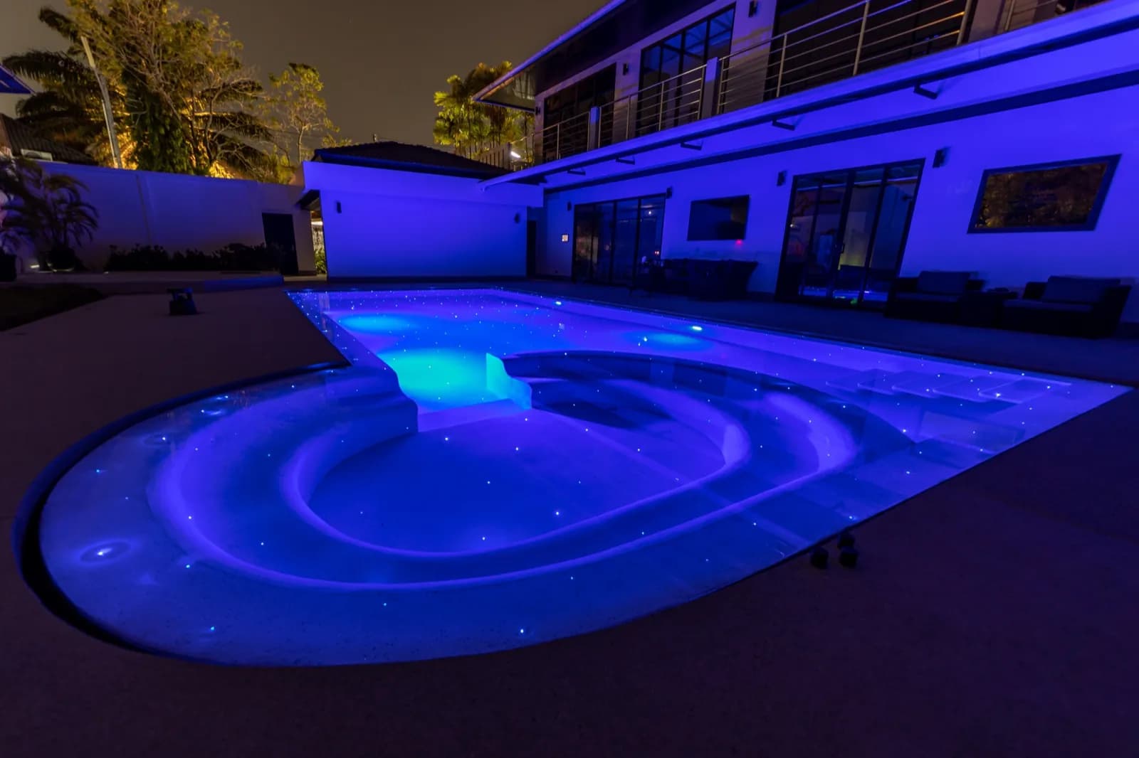 Keyhole pool and villa facade washed in violet LED light