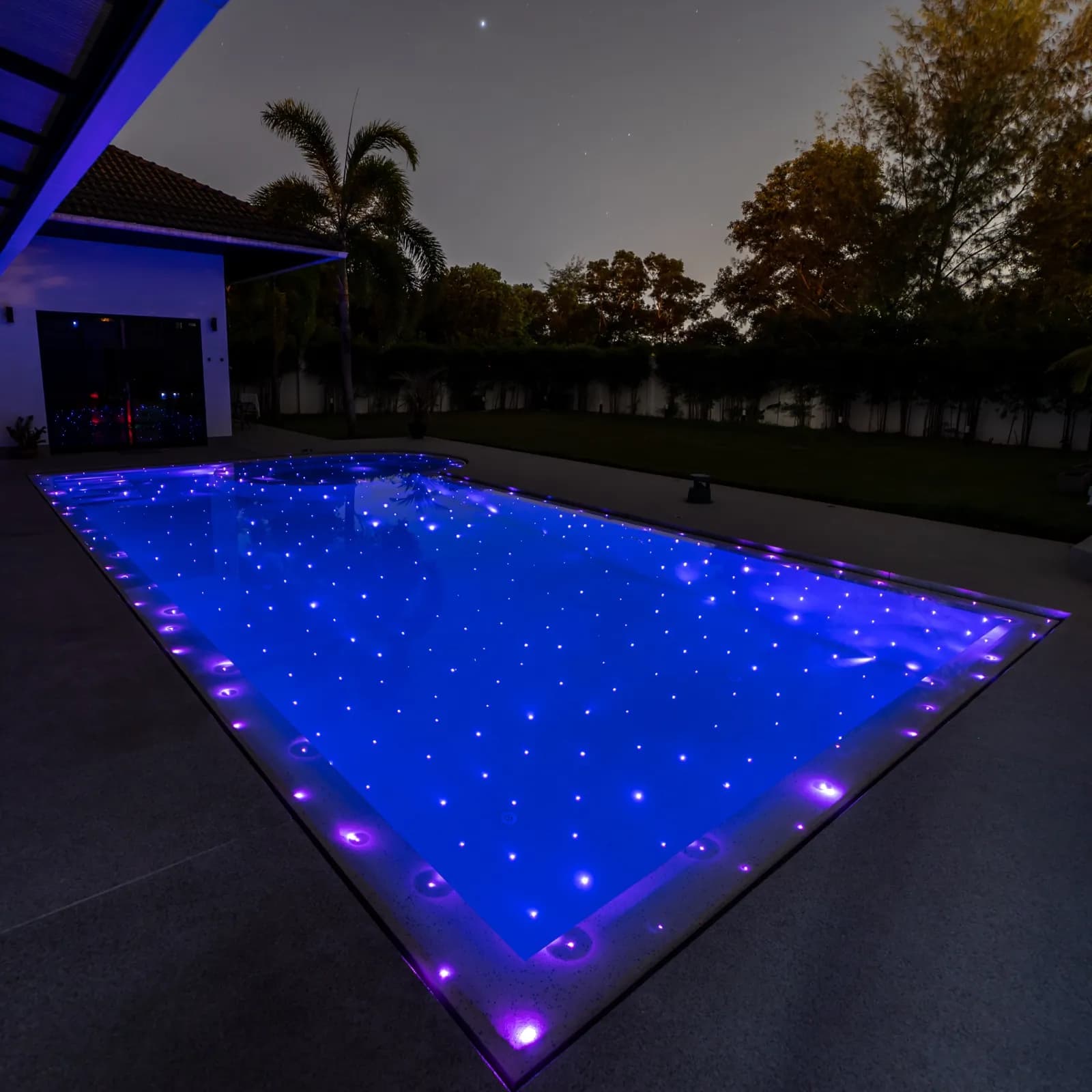 Pool sparkling with violet fibre-optic stars under a night sky