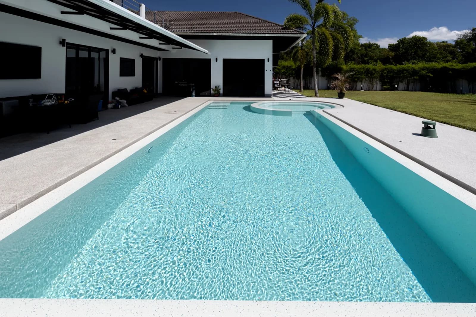 Long rectangular pool with sunlit ripples over a pale pebble finish