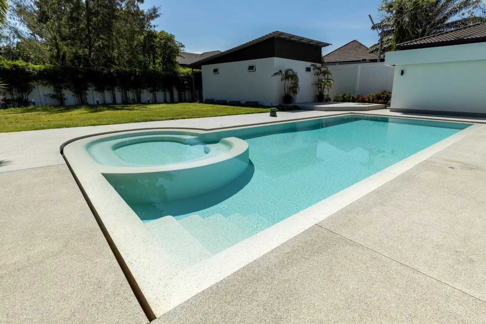 Bright aqua pool with a raised round spa end set in a tropical garden