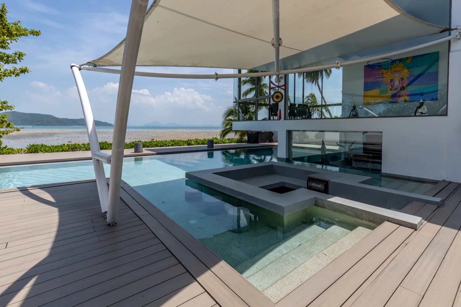 Sunken in-pool lounge under a sail shade facing the sea