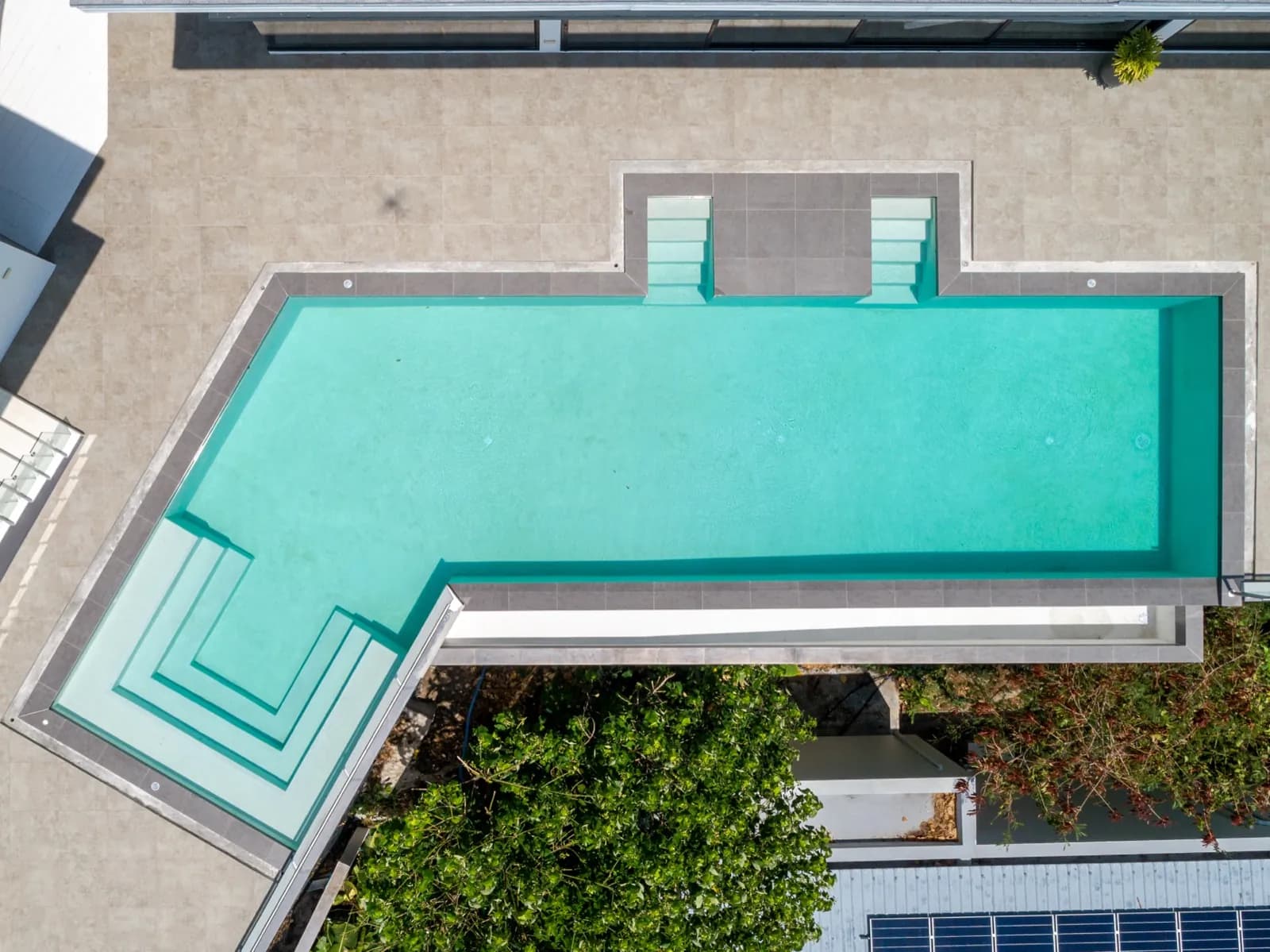 Overhead drone view of an L-shaped pool with wide entry steps