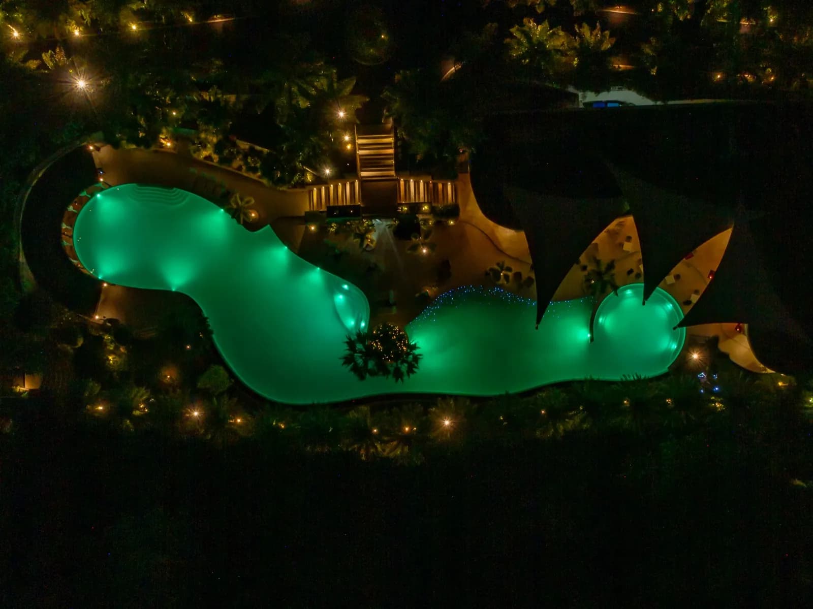Overhead night drone shot of the lagoon pool lit green