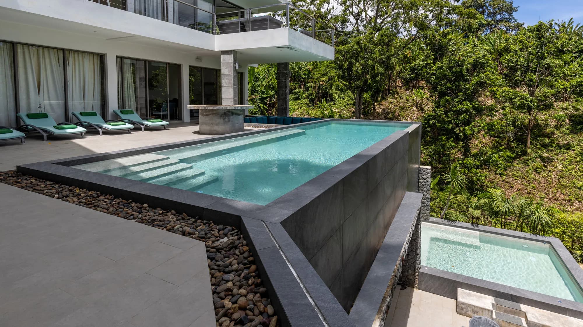 Hillside villa infinity pool with a dark glass-tile edge