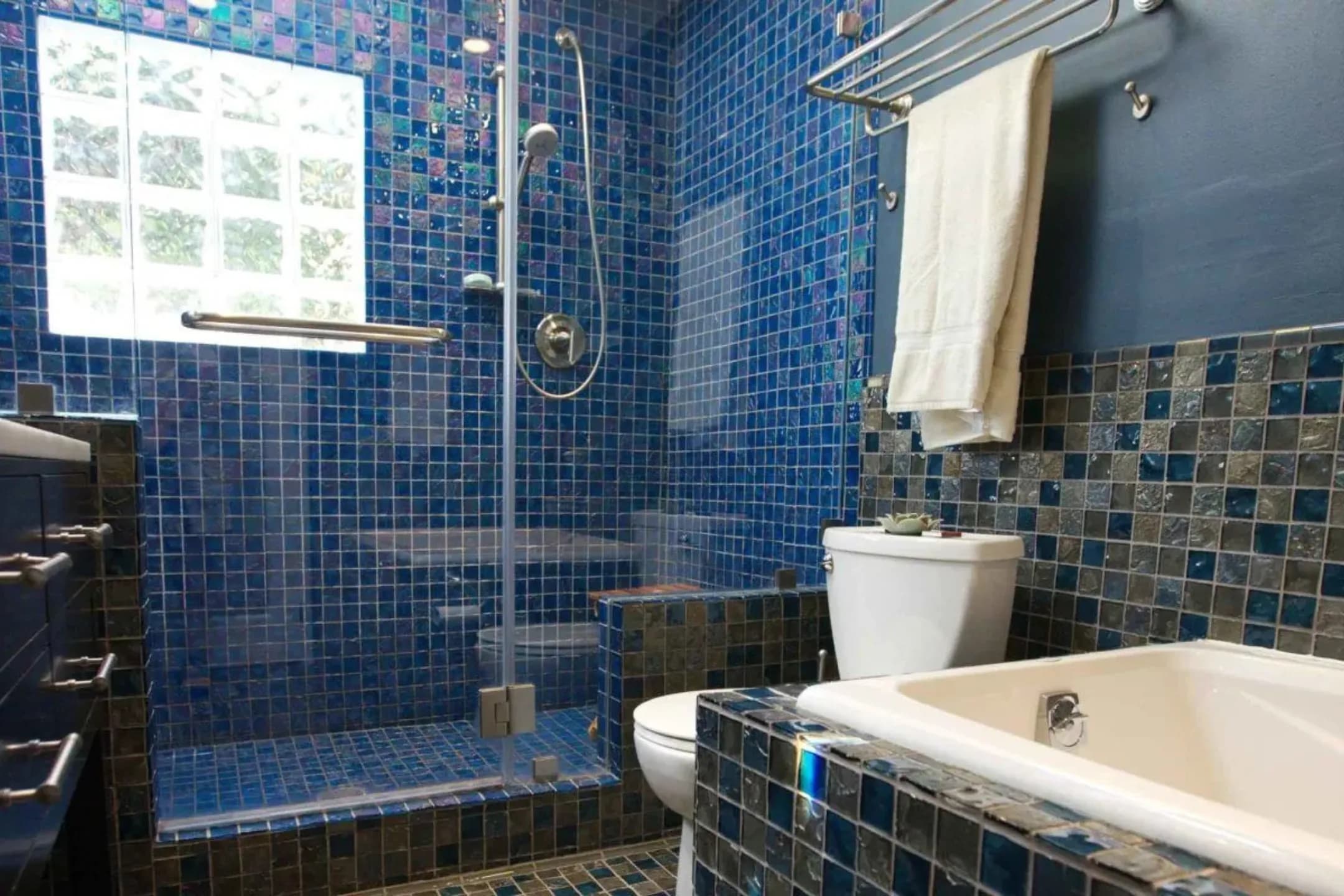 Bathroom shower and bath clad in blue Lightstreams glass tile