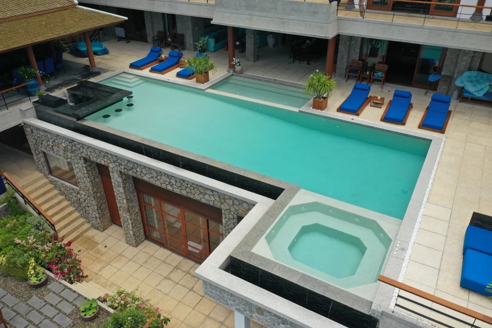 Octagonal spa pool set into the corner of a stone-clad infinity pool