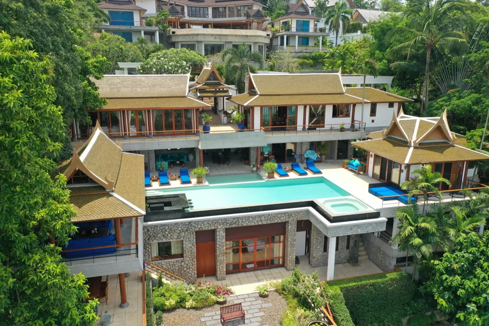 Thai villa and L-shaped infinity pool framed by tropical trees on a Phuket hillside