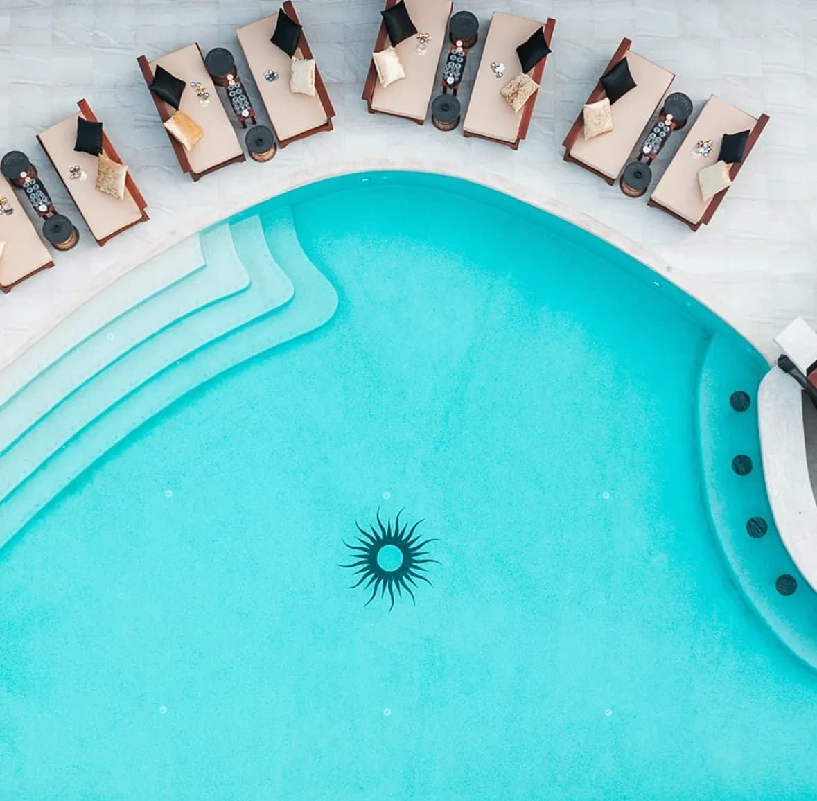 Bright turquoise pebble finish with sweeping steps, the Carpe Diem logo and a curved row of daybeds