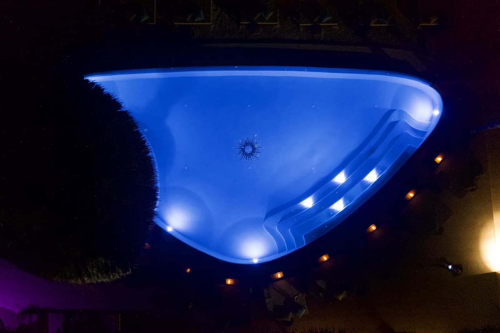 Pool glowing cobalt blue at night with lit step lights