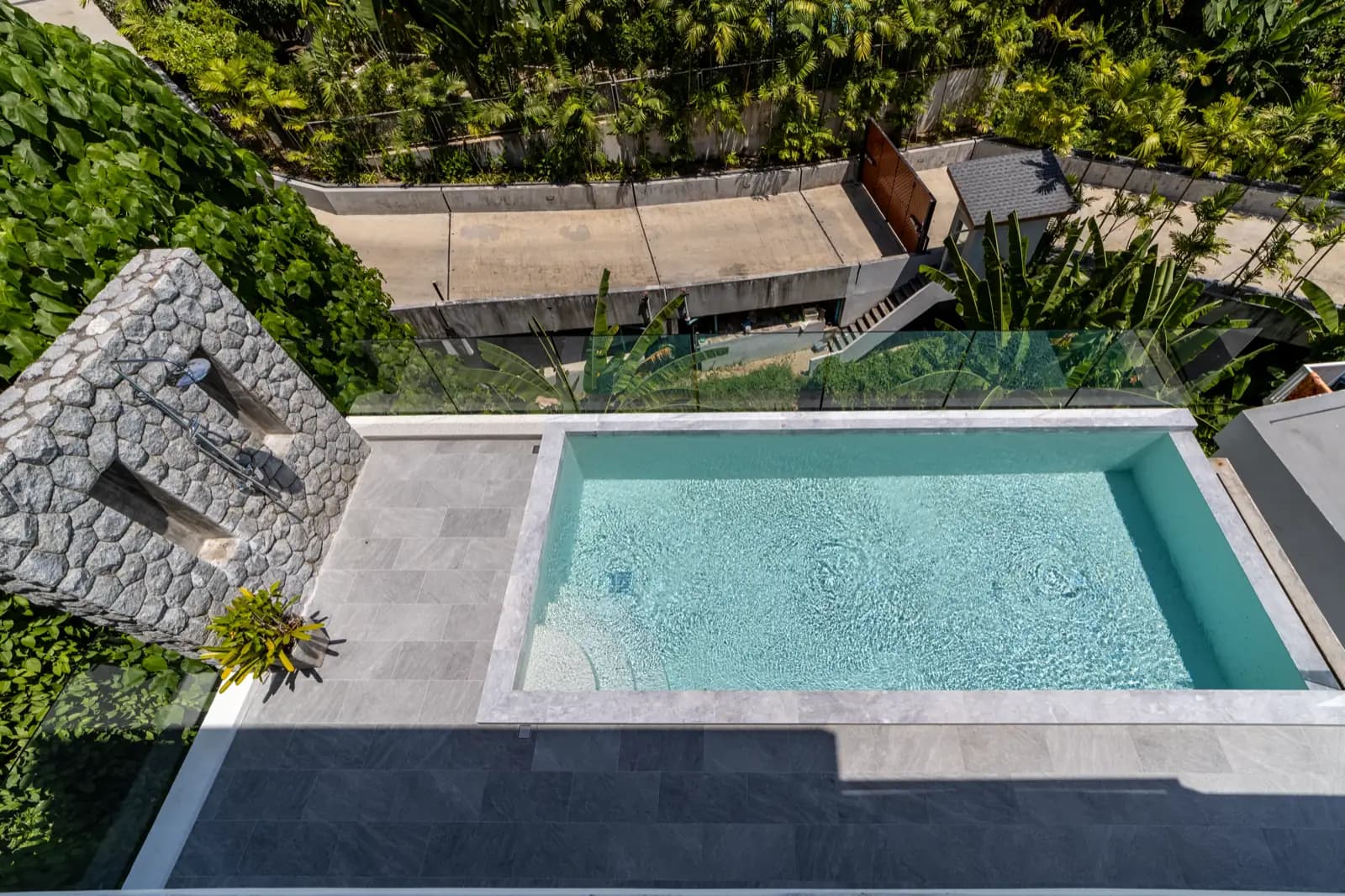 Aerial view of a terrace pool framed by marble coping and tropical planting