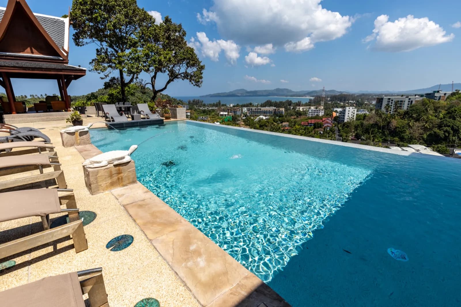 Sunlit infinity pool with rippling light-aqua water and sun loungers
