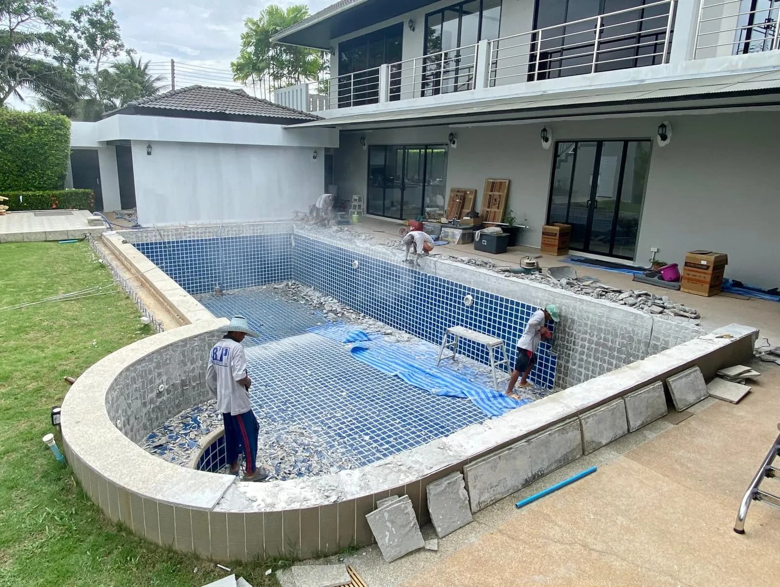 PebbleTec Thailand crew stripping old tiles to prepare a pool for its new finish